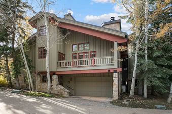 The Cache at Silver Lake 12 is a multi-story building with a warm facade, red-trimmed windows and doors, a balcony, and a garage, surrounded by autumn trees.