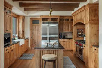 A modern rustic kitchen at Hord Mountain Retreat with warm wood cabinetry, a central island, and high-end stainless steel appliances.