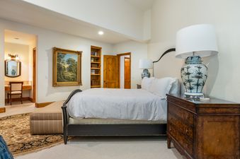 An elegant master bedroom at Holden Estate with a queen bed, a classic wooden nightstand, and an en-suite vanity visible in the background.