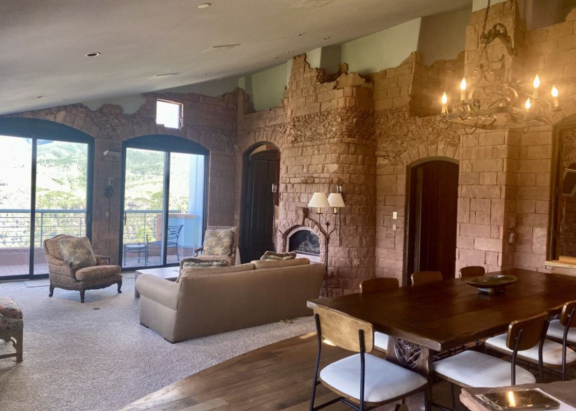 A modern living room with a stone fireplace, a large couch, and a dining table.