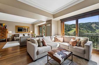 A large living room with a sectional sofa and a view of a green mountain.