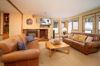 The Iron Horse J1309 living area features two comfortable brown leather couches, a fireplace, and a flat-screen TV.