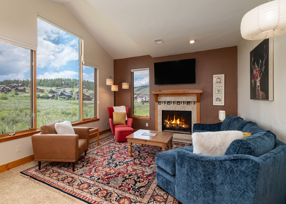 The living room at 2002 Lupine Lane features a cozy fireplace, comfortable seating, and large windows with scenic views.