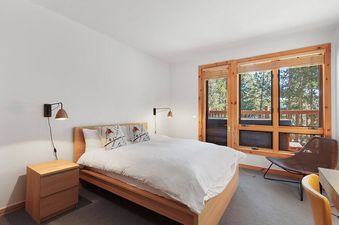 A bedroom with a bed, nightstands, and a view of the mountains.