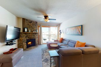 Living room with a fireplace, a couch, a TV and a view of the mountains from a window