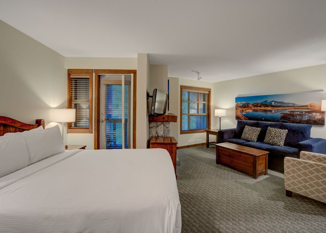 A cozy studio suite at Blackcomb Springs Premium Studio features a king-size bed and a comfortable living area with a sofa and armchair.