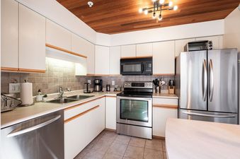 Fully equipped modern kitchen in the Foxglove 1 unit featuring stainless steel appliances and wood-paneled ceiling.
