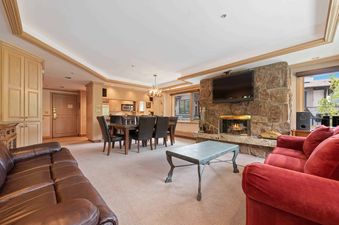 Living room of Lodge Tower 377 3BR with fireplace, couches, dining table and chairs.