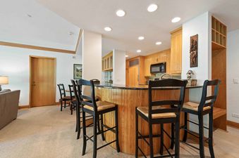 A kitchen with a breakfast bar, a microwave, and a refrigerator.