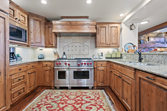 The kitchen in Grand Lodge Three Bedroom Deluxe 308 features stainless steel appliances, wood cabinetry, and granite countertops.