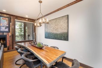 Dining area in Lorian 7 featuring a unique wooden table and modern chandelier.