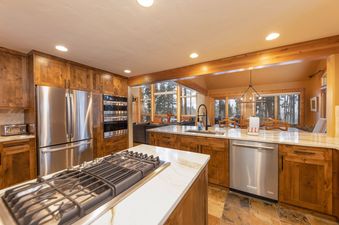 The kitchen at Fairview Lodge features a large island with a gas range, stainless steel appliances, and wood cabinetry, creating a luxurious culinary space.