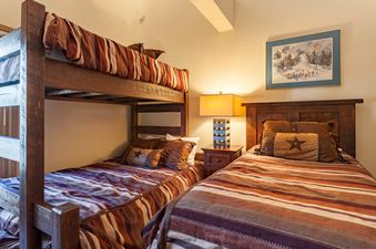 A cozy bedroom in Kutuk 203 with a rustic wooden bunk bed and a twin bed, decorated with earth-toned bedding.