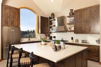 A modern kitchen with wood cabinets, stainless steel appliances, and a large island with seating.