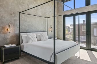 A modern bedroom with a four-poster bed and a balcony view in SkyRidge 1868.