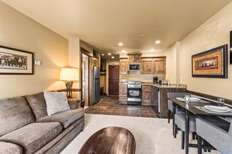 An inviting open-concept living and kitchen area featuring a comfortable sofa, a modern kitchen with wooden cabinetry, and a dining table set for guests.