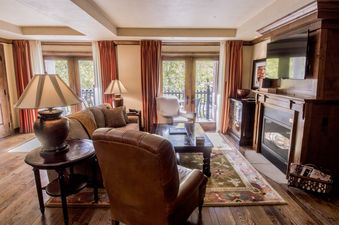 A spacious and inviting living room features elegant furnishings, a fireplace, and large windows leading to a balcony.