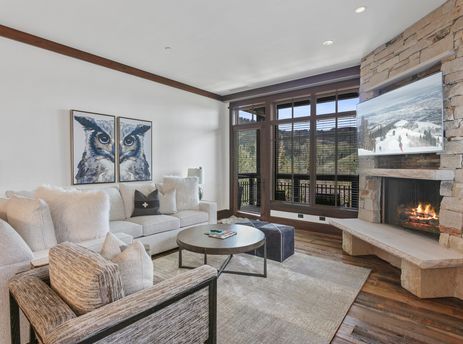 Cozy living room in Arrowleaf 209 with a stone fireplace, white sectional, and large scenic windows.