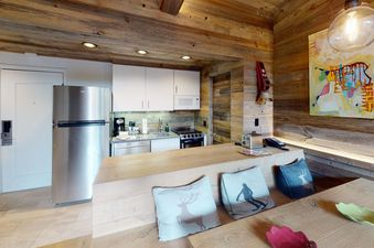 A cozy, well-equipped kitchen with a dining area and a view of a ski-in ski-out slope.