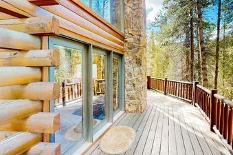 The Atkins Cabin deck is made of wood and has a wooden railing, looking out into the woods.