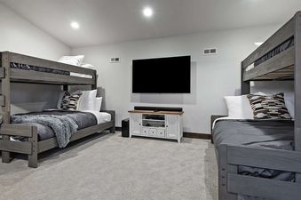 A modern bedroom with two bunk beds and a large television on the wall.