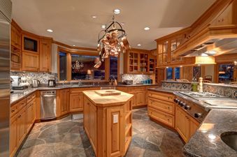Fully equipped wooden kitchen of Horstman 4930 with a central island and stone flooring.