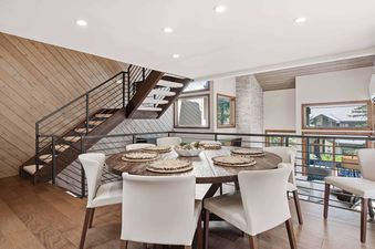A modern dining area at Ridgepoint Townhome 166 featuring a round wooden table, white chairs, and a staircase.