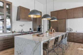 Modern kitchen with custom wood cabinetry and a large marble island at SkyRidge 1152.