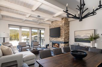 The living room of Moonlight Basin 16 Wildwood, featuring a fireplace and large windows with mountain views.