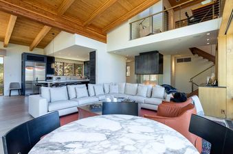 The grand living area features a roaring fireplace, creating a cozy ambiance at Fairway Views Estate At Vail Golf Club.