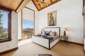 A spacious and bright bedroom with a king-sized bed, rustic furniture, and large windows offering panoramic mountain views at Snow Pine Lodge at Deer Valley.