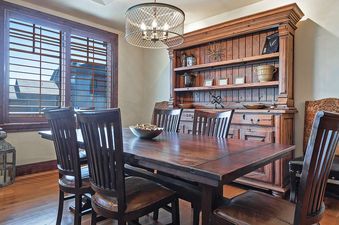 The dining area features a large wooden table and chairs, complemented by a distressed wood hutch filled with decor.