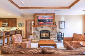 A living room with a fireplace, a large TV, and a leather couch.