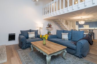 A living room with two blue couches, a coffee table, and a fireplace