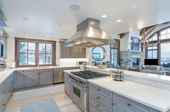 A modern kitchen with stainless steel appliances, a gas stove, and a large window with a view of a snowy mountain range.