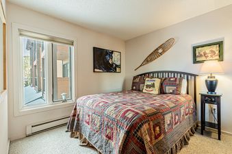 A cozy bedroom with a queen-sized bed, a window overlooking the snowy mountains, and rustic decorations.