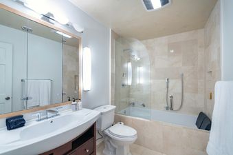 A modern, white bathroom with a large bathtub, a toilet, and a sink.