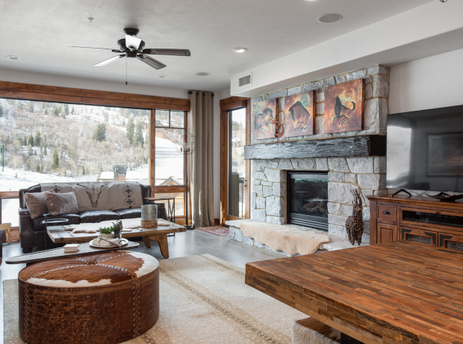 The living room of the 132 Two Bedroom Black Diamond Lodge features a fireplace, a flat screen TV, and a large window offering a view of the ski slopes.