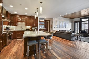 A spacious great room in Arrowleaf Lodge 311 featuring a gourmet kitchen with a large island and a comfortable living area with a large sofa.