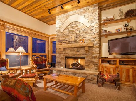 The cozy living area of Kutuk 112 featuring a stone fireplace and rustic wooden decor.