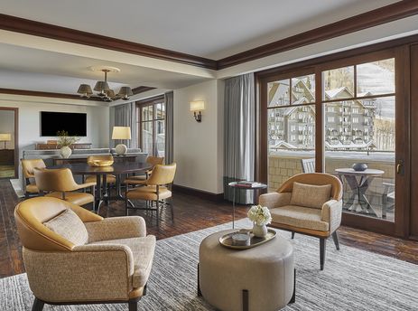 A spacious Montage Alpine Residential Suite features a comfortable living area with elegant furnishings, a dining space, and large windows revealing a snowy mountain landscape.