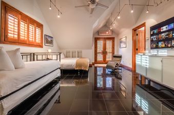 A bedroom with two twin beds, a TV, and a comfortable armchair.