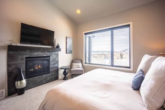 The bedroom in Frostwood Villa 4302 features a comfortable bed, a fireplace, and a beautiful view of the mountains.