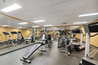 The well-lit fitness center at Morning Eagle 209 features various exercise machines, including treadmills, ellipticals, and weight machines, with mirrors lining one wall.