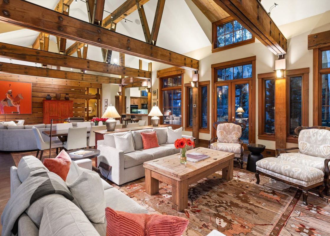 The living room of A Creekside Lodge features a large sectional sofa, a coffee table, and two armchairs, all arranged around a rustic area rug.