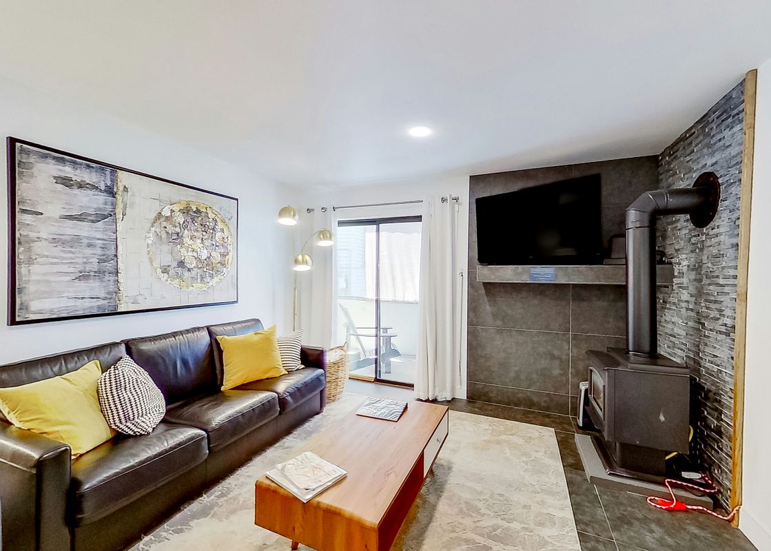A living room with a couch, coffee table, fireplace, and a view of a balcony.