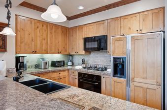 A fully equipped kitchen at Villa Montane 226, featuring wooden cabinetry, modern appliances, and a spacious granite countertop.