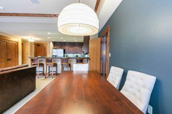 A dining table with four chairs, a couch, and a kitchen in the background.