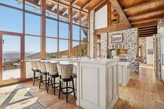 The kitchen at Snow Pine Lodge at Deer Valley features a large island with bar stools and expansive windows showcasing panoramic mountain views.