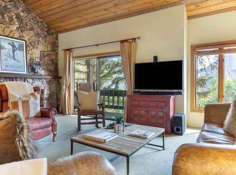 A spacious and inviting living room at 88 Ridge Point features a large fireplace with a stone chimney, comfortable seating, and a large TV.